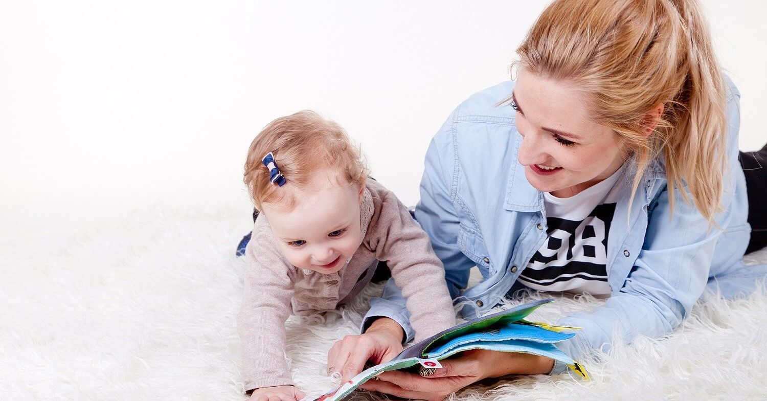 Ein Baby liest zusammen mit seiner Mutter ein Bilderbuch