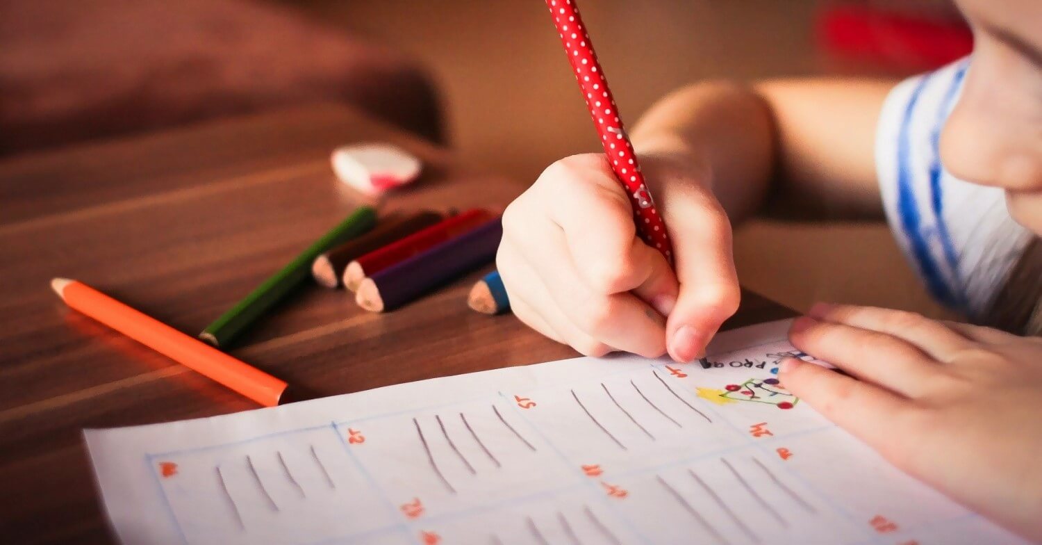Ein Kind hält einen Bleistift und lernt mit einem Übungsheft zu schreiben