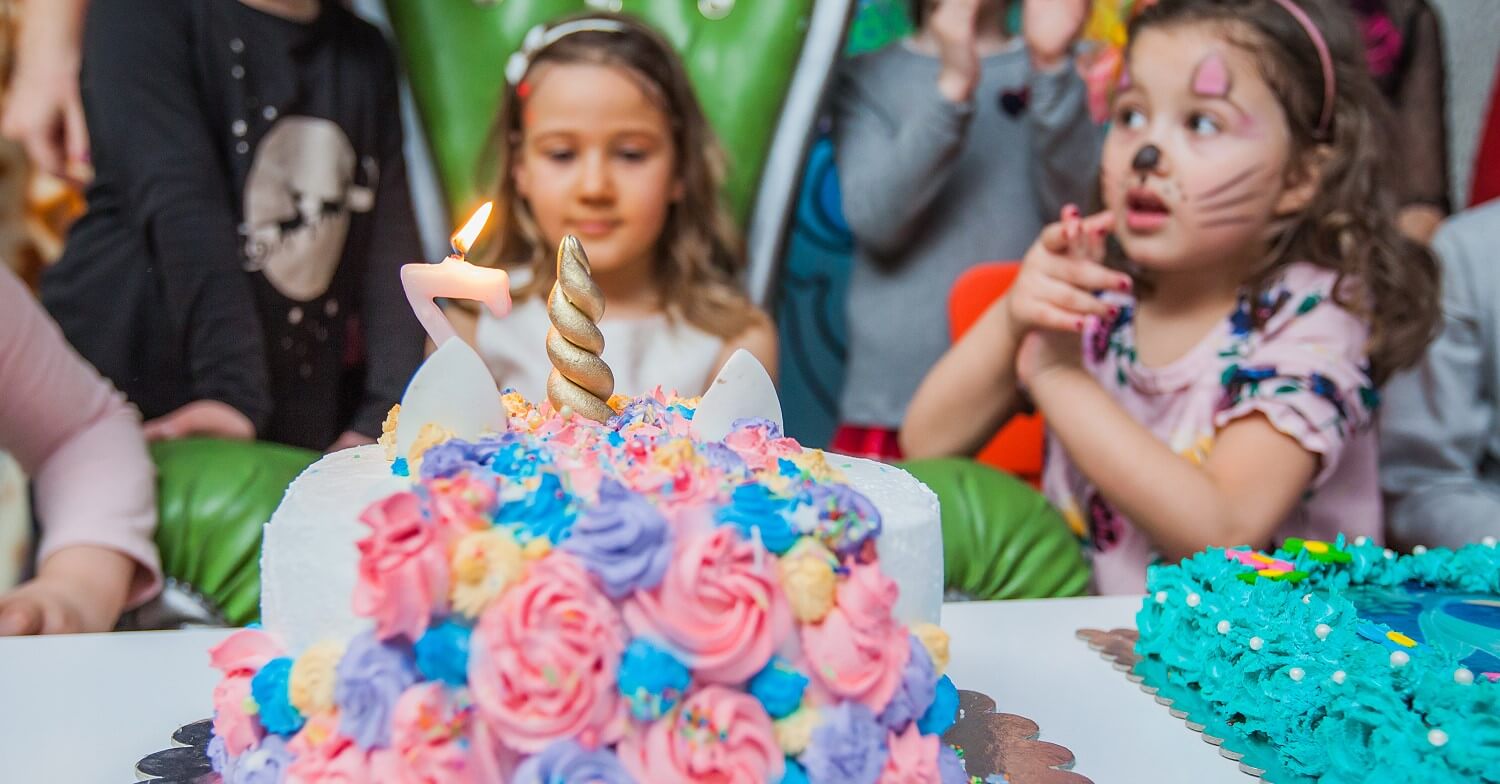 Geburtstagstorte mit Himbeeren und Sahne sowie Deko aus Einhörnern und Regenbogen