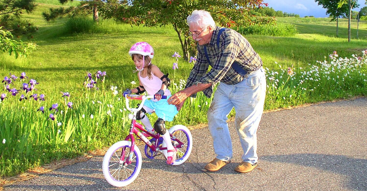 Großvater bringt seiner Enkelin das Radfahren bei