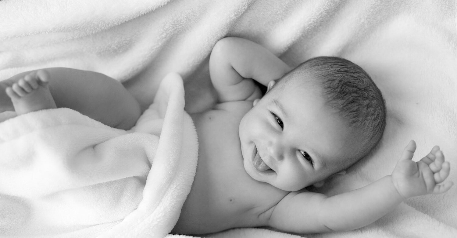 Ein lachendes Baby geht zur U-Untersuchung beim Arzt. Es lacht und strampelt