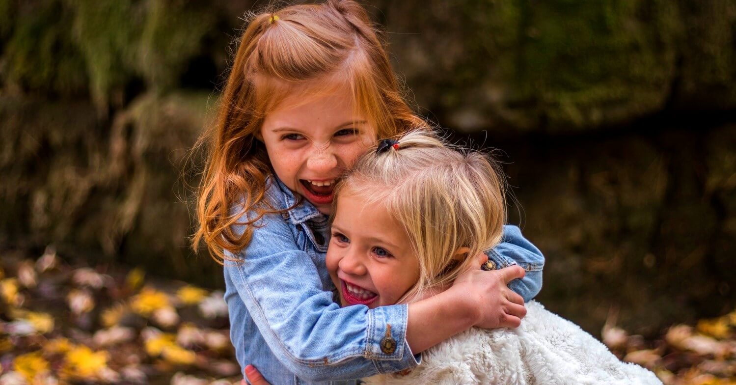 Zwei kleine Mädchen lachen und umarmen sich: Freundinnen