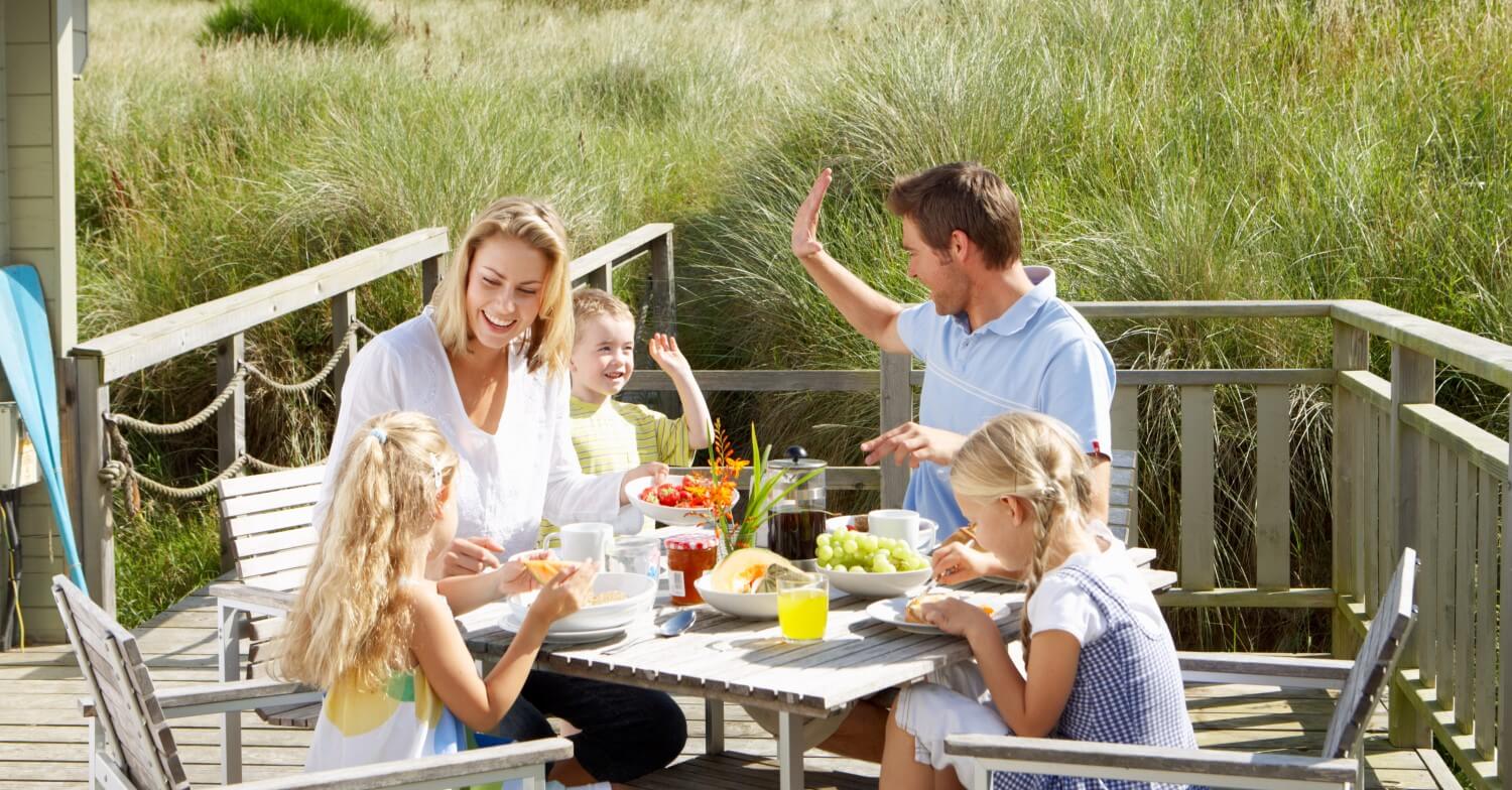 Eine Familie mit drei Kindern frühstück auf der Terrase eines Strandhauses